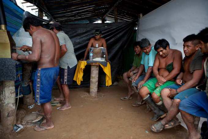 In this May 3, 2014 photo, wildcat miners wait their turn to melt their amalgam of gold and mercury to burn off the mercury in the temporary home of a gold buyer in La Pampa in Peru's Madre de Dios region. It's not just miners who are threatened with economic catastrophe from the government¹s campaign to wipe out illegal mining operations, said a mining camp cook. For every miner there is a family that eats because he works, she said. (AP Photo/Rodrigo Abd) ORG XMIT: ABD118